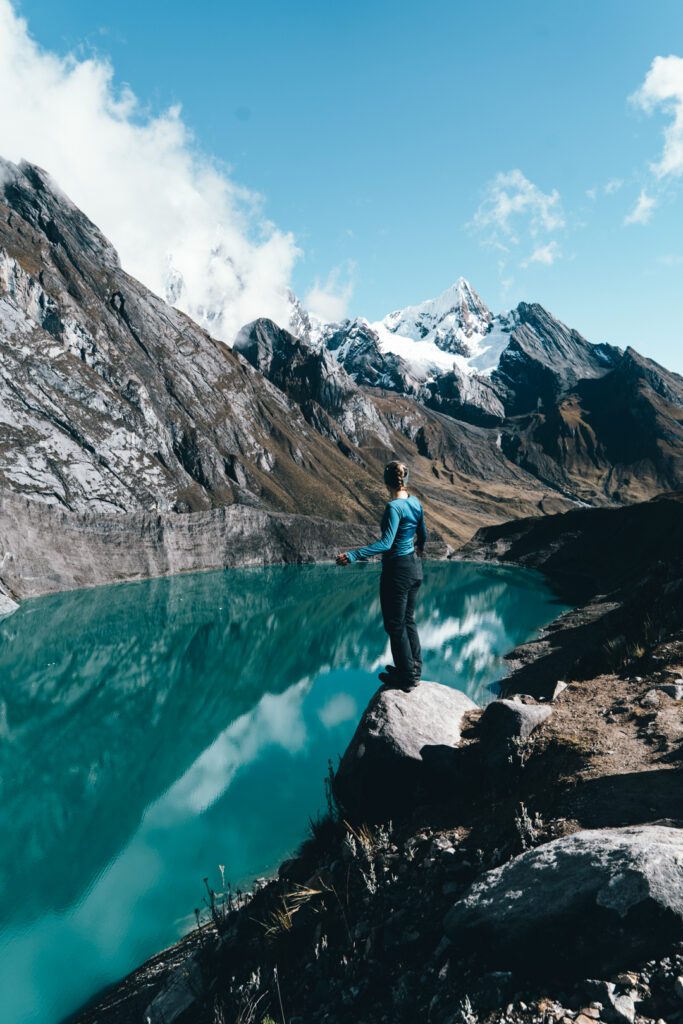 Woman poses in front of glacial lake during Peru's Huayhuash trek
