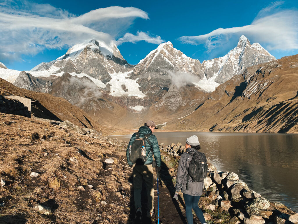 Two people trekking Huayhuash near day 2 campsite with glacial lake