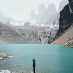 Woman standing at the base of blue lake in Torres Del Paine Chile Patagonia