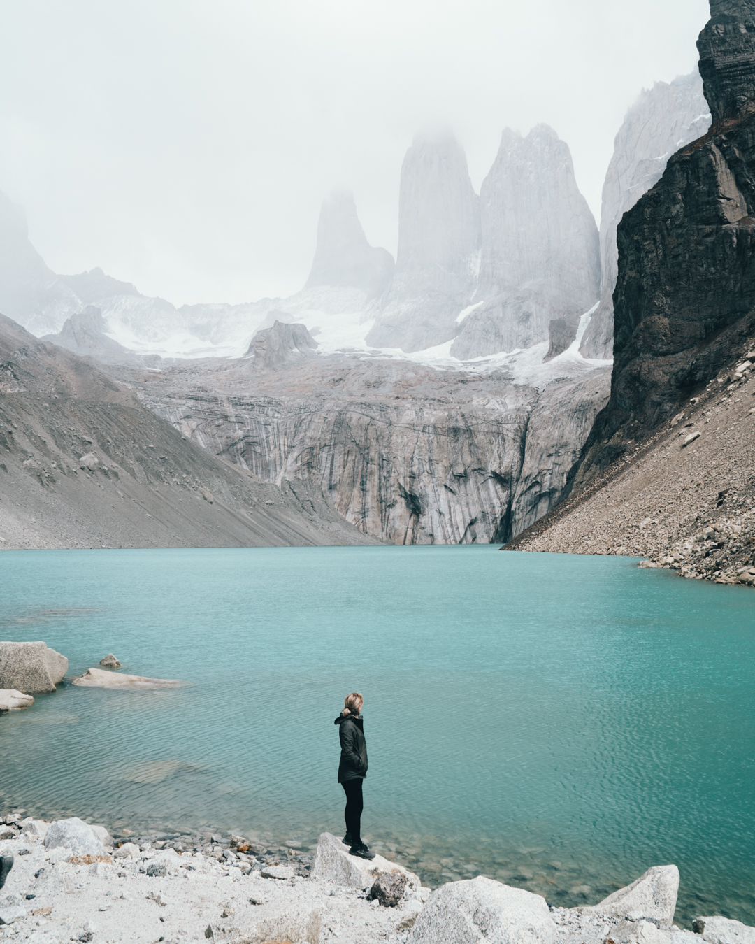 Woman standing at the base of blue lake in Torres Del Paine Chile Patagonia