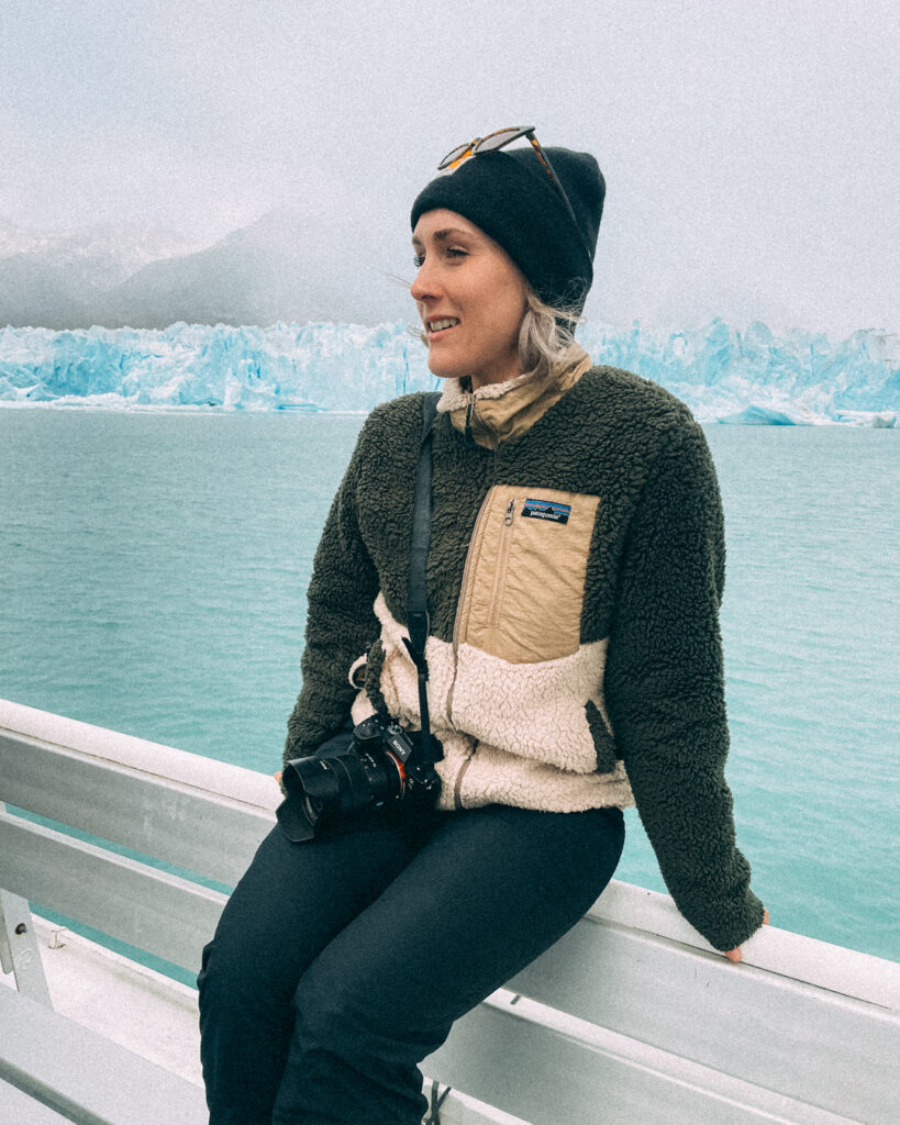 woman poses for photo in front of Perito Moreno glacier in Argentina
