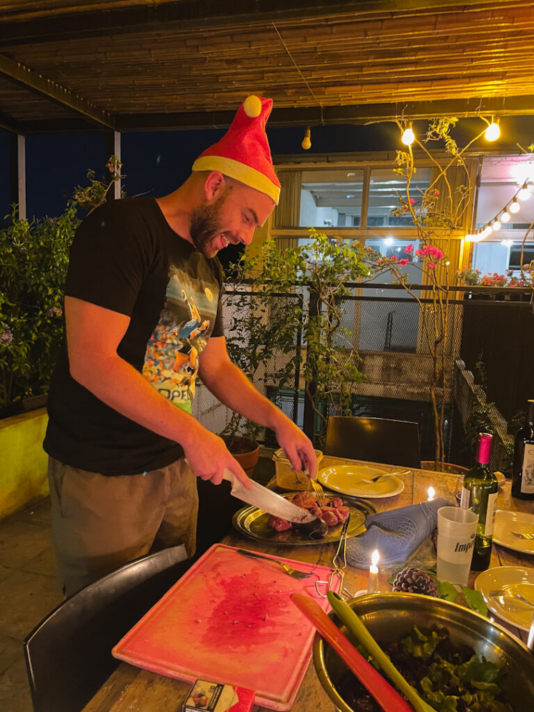 man in christmas hat cutting steak in buenos aires in Christmas asado
