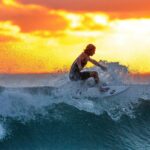 Man surfing with sunset behind